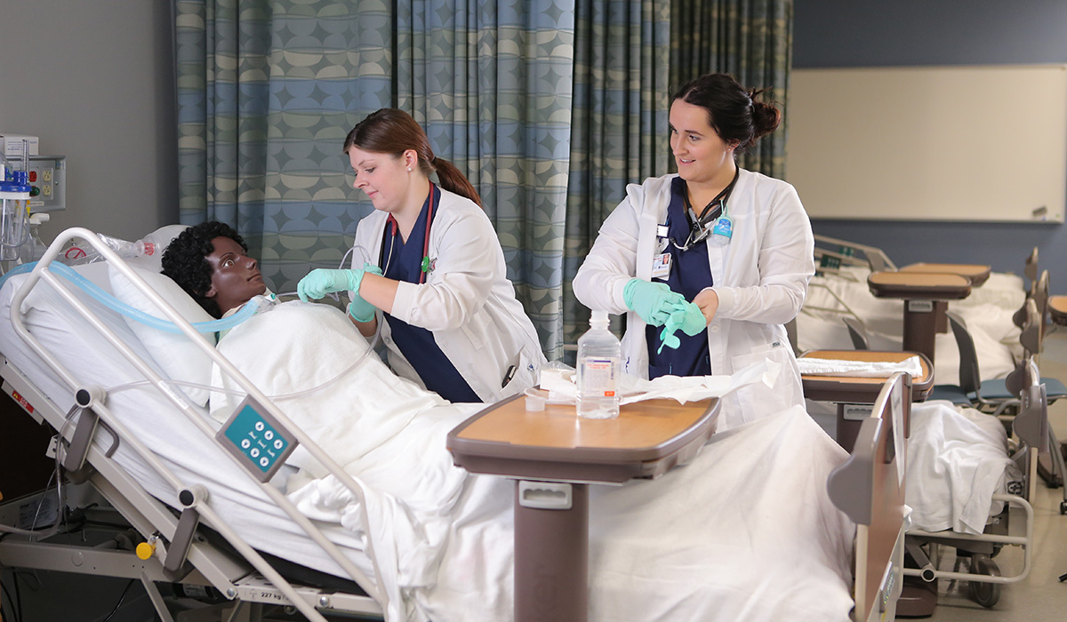 Two nursing students practicing on a dummy
