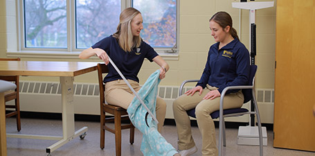 two students in a classroom one is using a tool to show the other