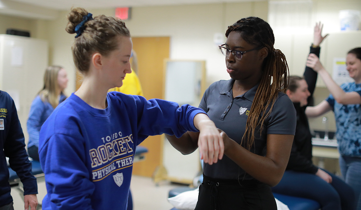 students practice clinical physical therapy movements in classroom