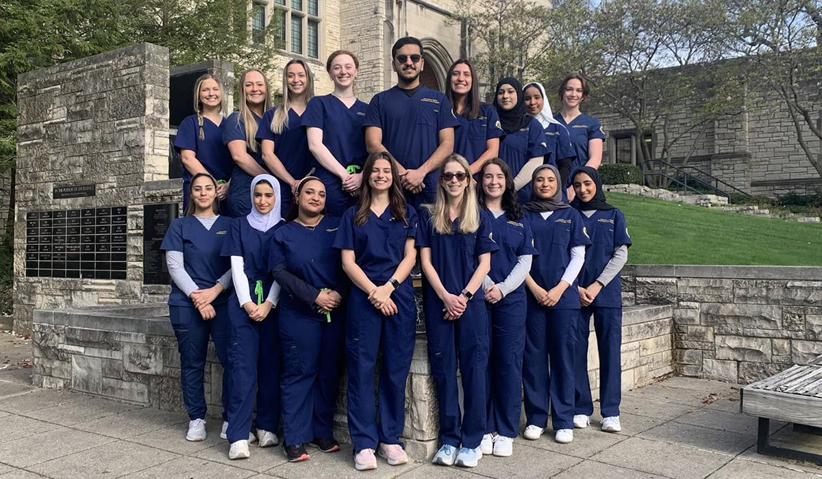a group of respiratory care students standing outside university hall taking a group photo