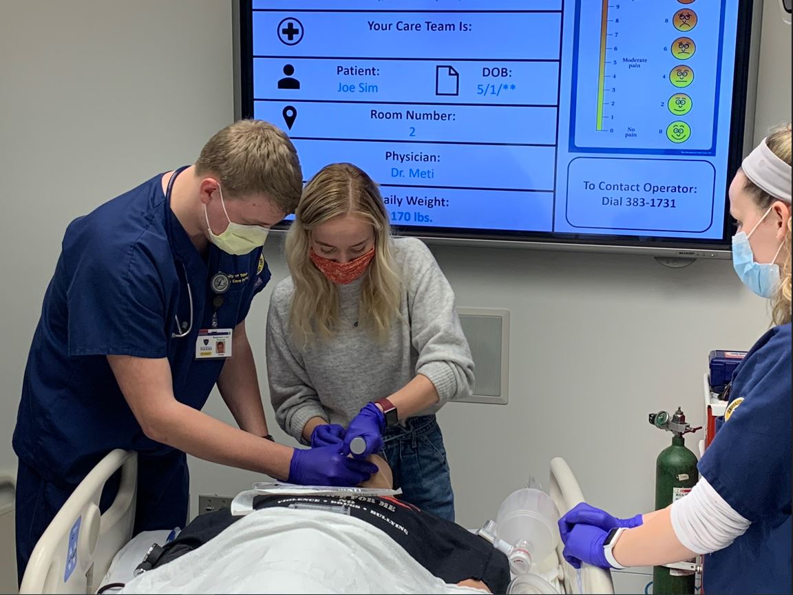 A male student and a female student attempt to intubate a simulation manikin.