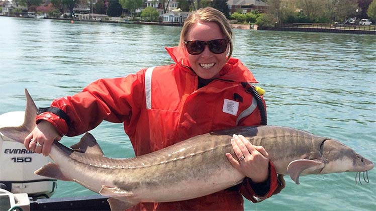 Photo of UT grad student holding a sturgeon.
