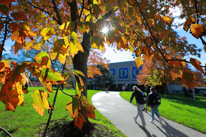 A group of people walking across UToledo's campus on a beautiful fall day.