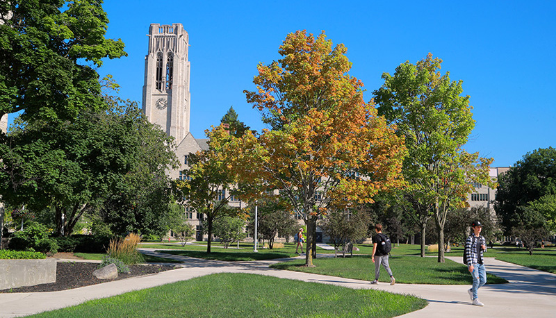 An outdoor view of UToledo's campus with clear blue skies and students walking around