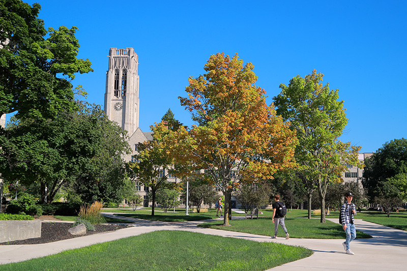 An outdoor view of UToledo's campus with clear blue skies and students walking around