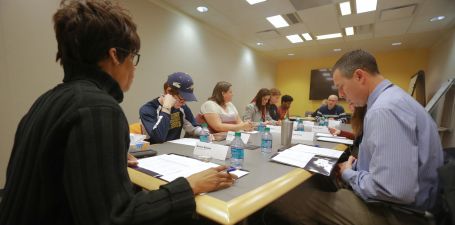 Group of people sitting at a long table and reviewing paperwork.