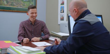 two people sitting across from eachother at a desk reviewing paperwork.
