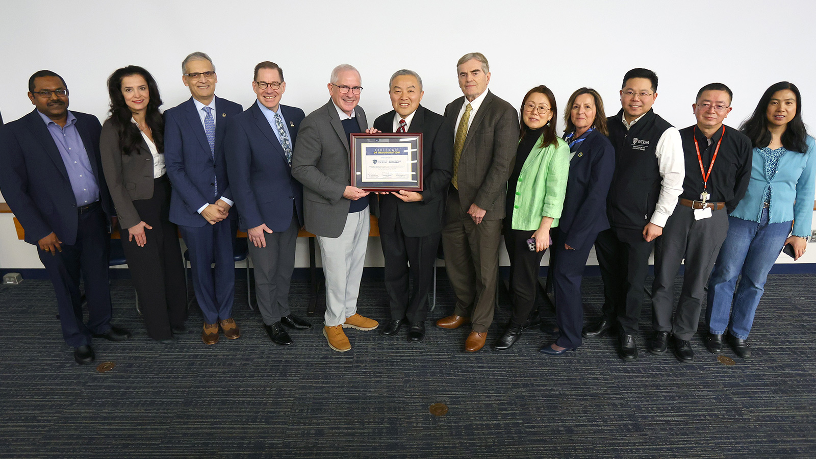 University administrators, faculty and institute members gather for a group photo holding a certificate recognizing the inauguration of the Northwest Ohio Cancer Research Institute at The University of Toledo.