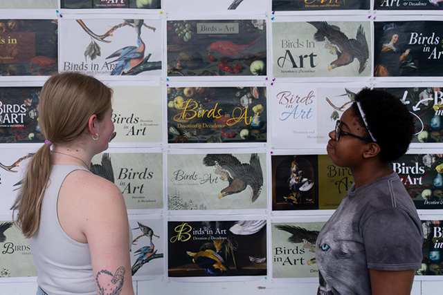 two female art students standing infront of an art exhibit for Birds in Art