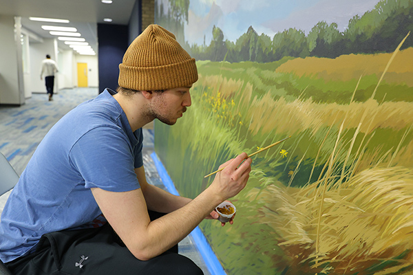 UToledo alumnus Liam Ginter works on a new native plant mural inside Carlson Library