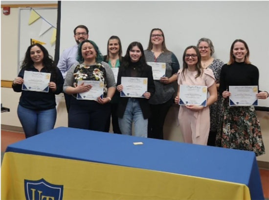 a group of students standing for a group photo holder an award papper