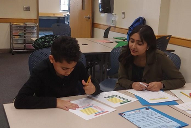a woman helping a kid work on an assigment in a classroom