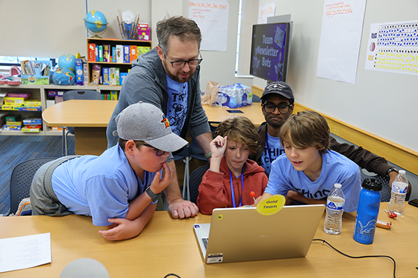 Student teachers work with children at a laptop