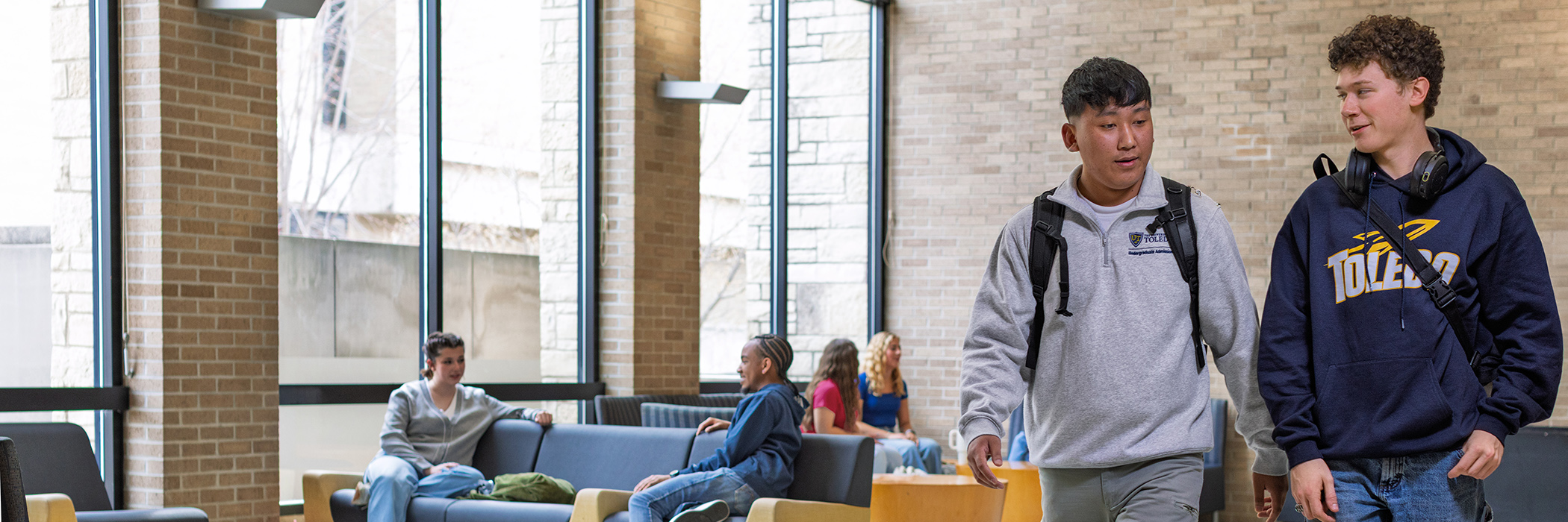 Students in the lancelot thompson student union, students are walking, others students are sitting on benches talking to eachother