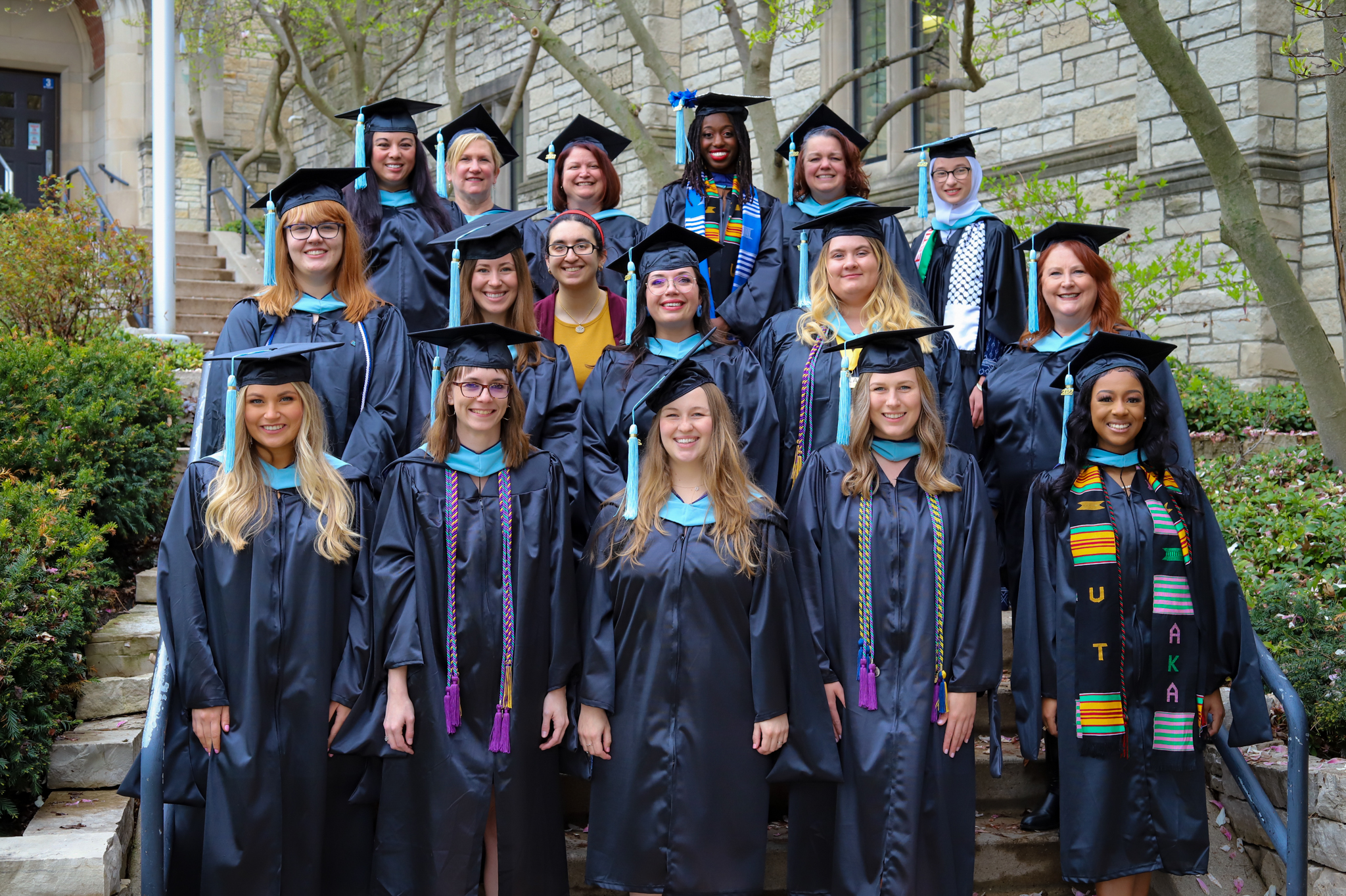 Group shot of Educational Studies graduates in caps and gowns on the steps of University Hall