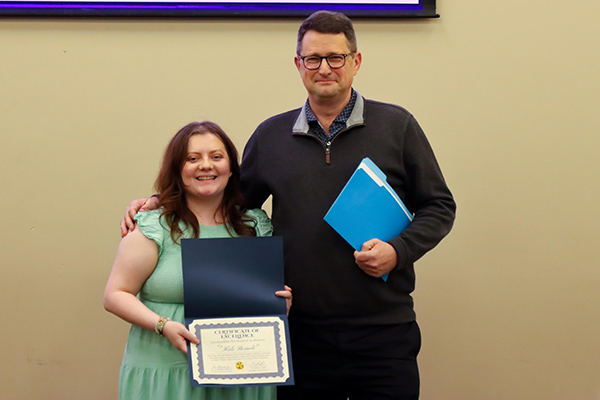History student standing with history faculty Barry Jackisch. The female student is holding an award certificate.