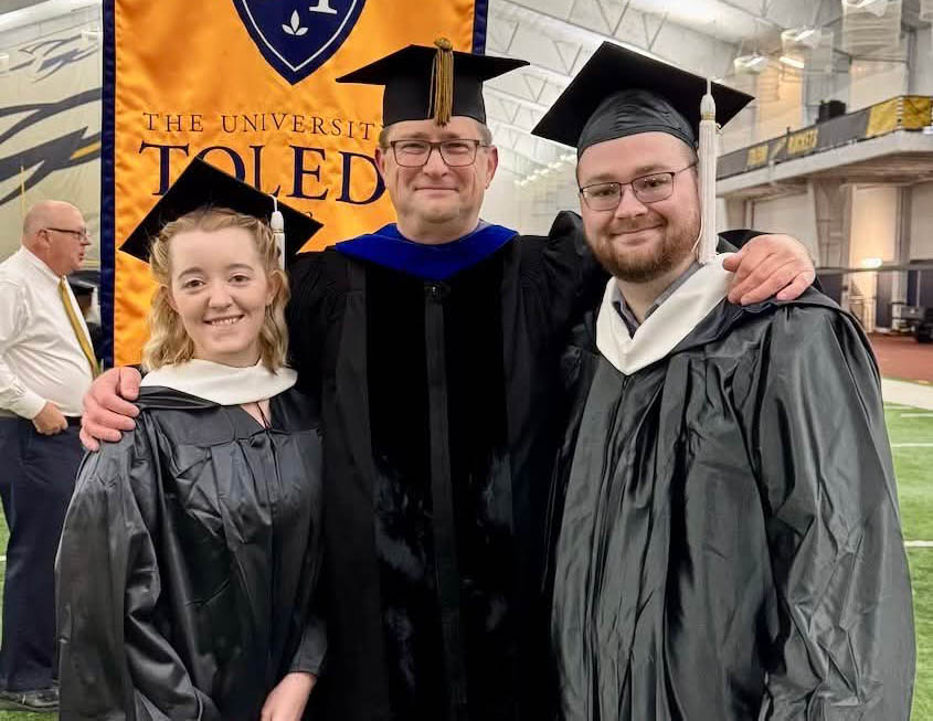 Two master students at commencement with Dr. Barry Jackisch