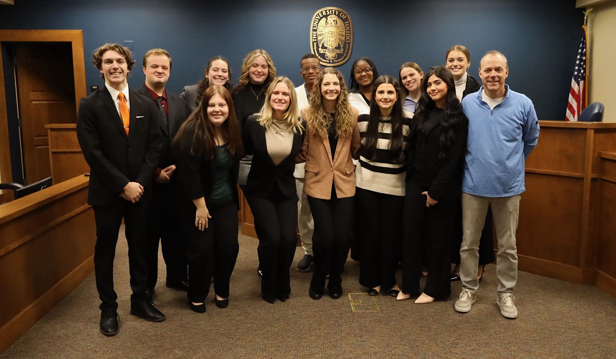 student in mock trial room standing together taking a group photo