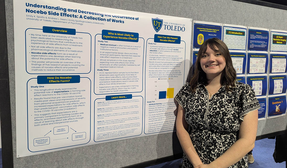 student standing in front of a research poster