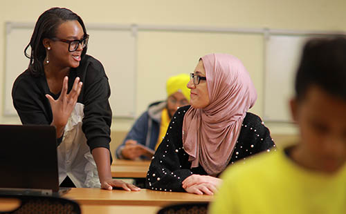 Two women talking to each other in a classroom