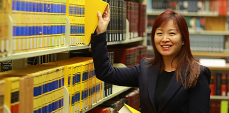 student pulling book from library shelf