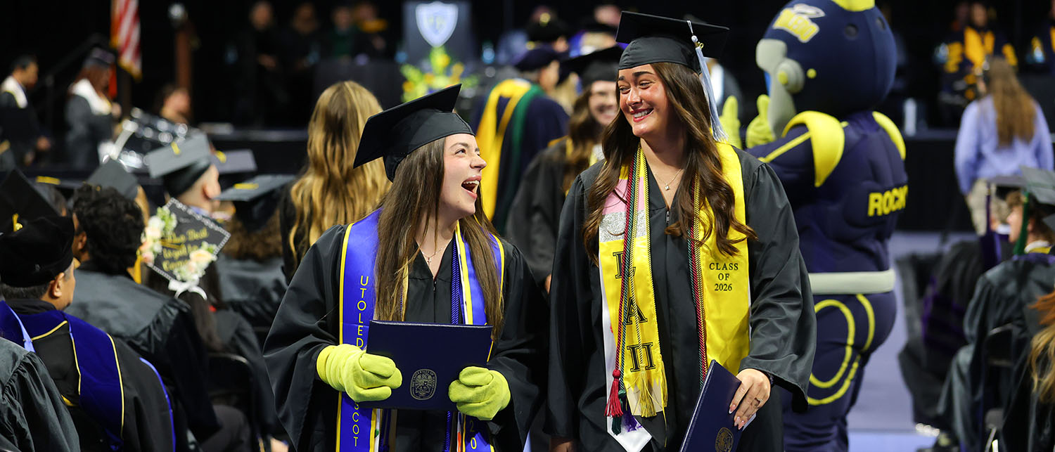 Rocky graduate class of 2026 walking down aisle at graduation with classmate