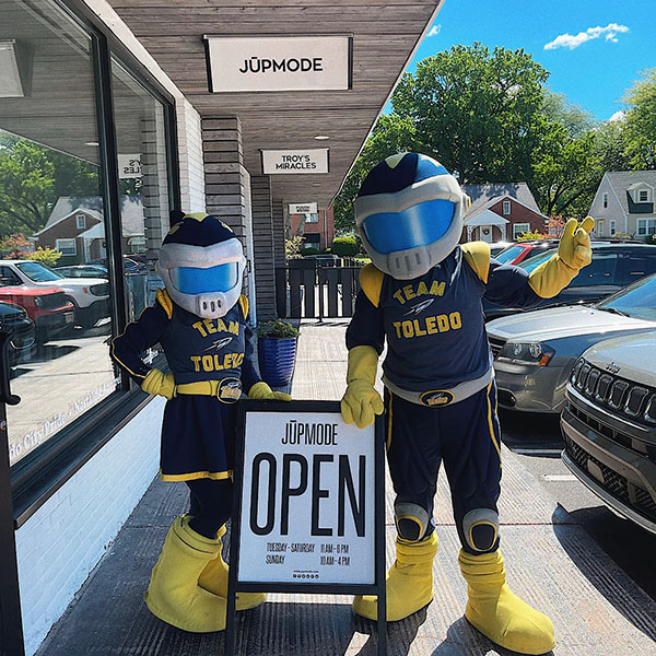 rocky and rocksy standing outside of Jupmode with a sign