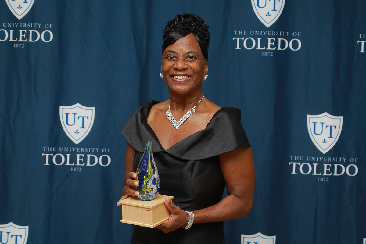 Dr. Ada D. Stewart at the Homecoming Gala holding her award in front of a UToledo backdrop.