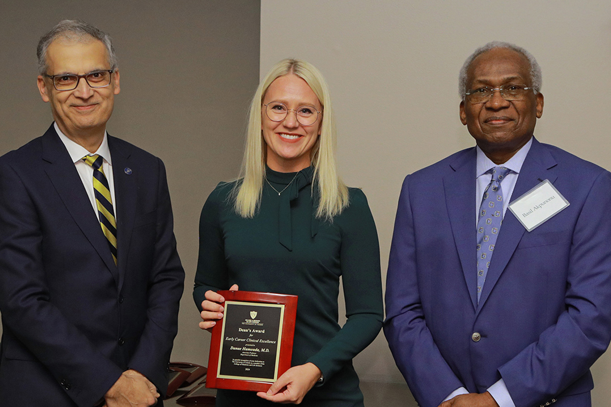 Dr. Danae Hamouda accepts her award for Early Career Clinical Excellence and poses for a photo with Dean Imran Ali and Dr. Basil Akpunonu at the Faculty and Staff Recognition Awards dinner.