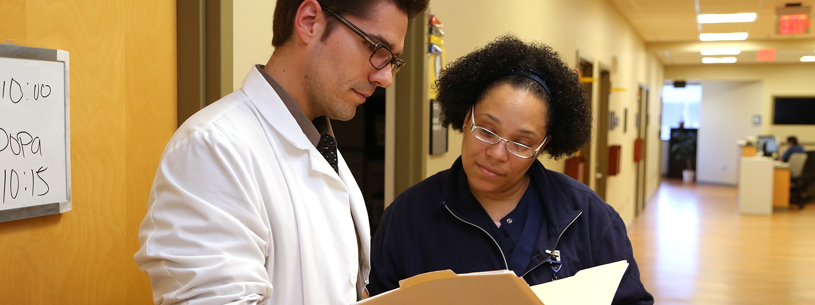 Two people looking at a folder with information inside