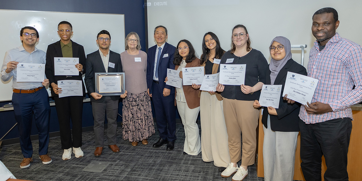 Graduate student award recipients stand with Dr. Williams and keynote speaker Dr. Huang, holding certificates and honors at the Graduate Research Annual Forum.