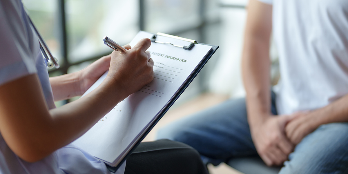 Stock photo of a healthcare professional taking notes during a patient consultation, focused on providing medical care and support in a clinical setting.