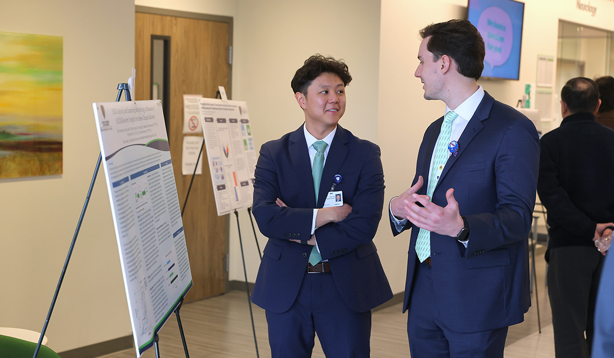 Third-year medical student Jason Suh discusses his research poster with another attendee during a neurology research poster session.