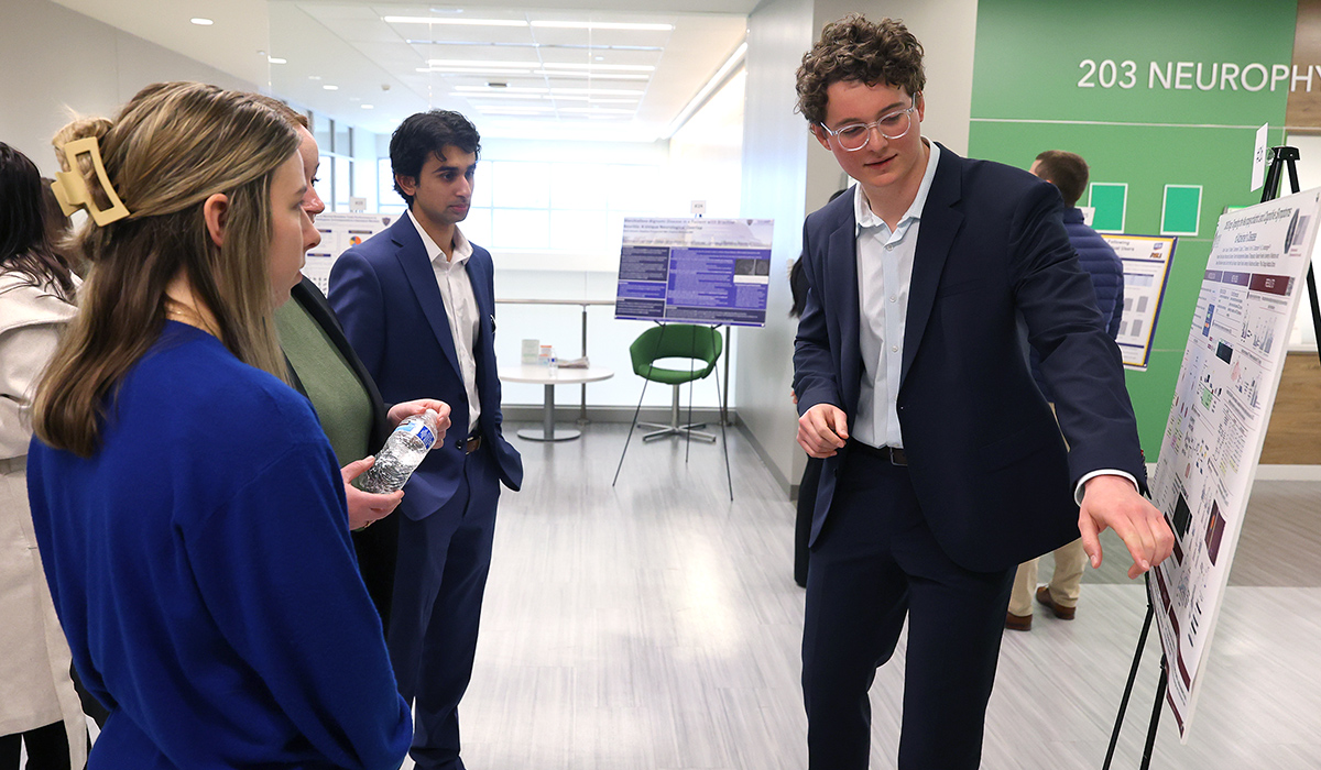 Second-year medical student Aidan R. Butler presents his research poster, "CNS Drugs Targeting the Neuropsychiatric and Cognitive Symptoms of Alzheimer’s Disease," to attendees during a neurology research poster session.