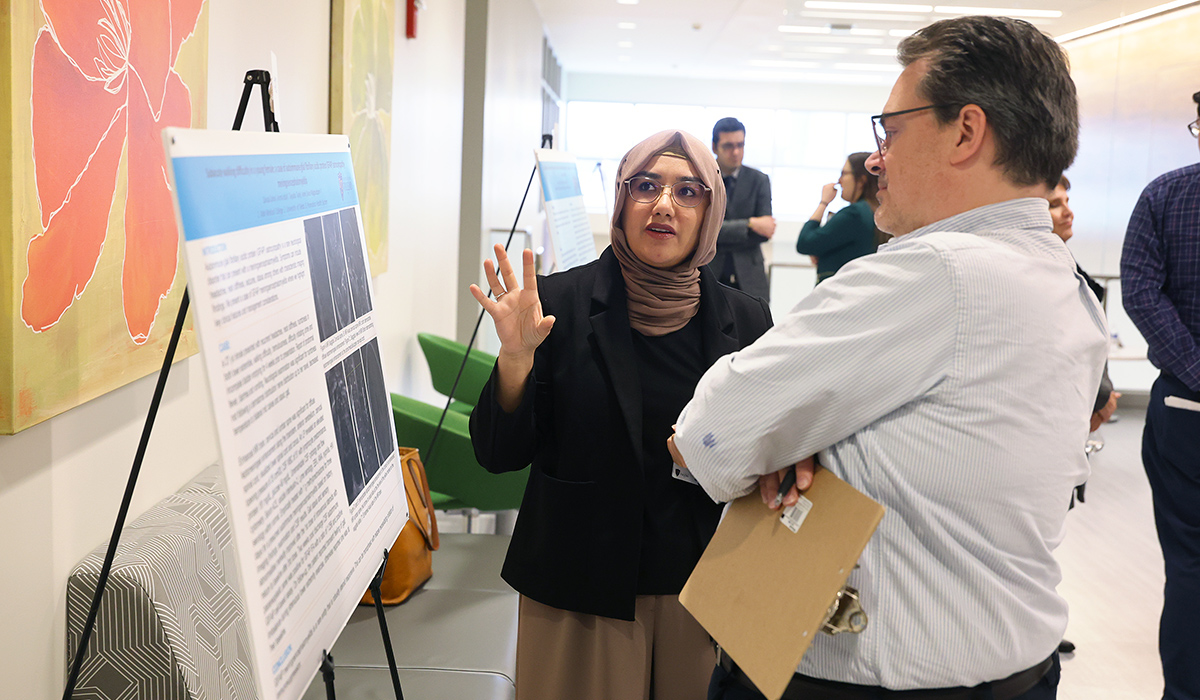 Neurology resident Dr. Zainab Zahra presents her research poster, "Subacute walking difficulty in a young female; a case of autoimmune glial fibrillary acidic protein (GFAP) astrocytopathy meningoencephalomyelitis," while discussing the case with Dr. James Burkett during a poster session.