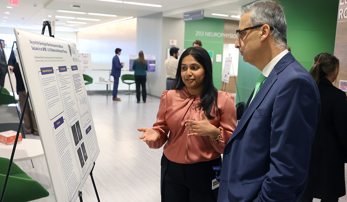 Third-year medical student Gayathri Kumar Plakkot presents her research poster, "Beyond the Genotype: Rare Development of ARIA and Seizures in an APOE ε3/ε3 Patient on Anti-Amyloid Therapy," while discussing the work with Dr. Imran Ali during a poster session.