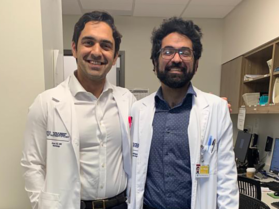 Two residents are pictured in a clinical setting wearing white coats.