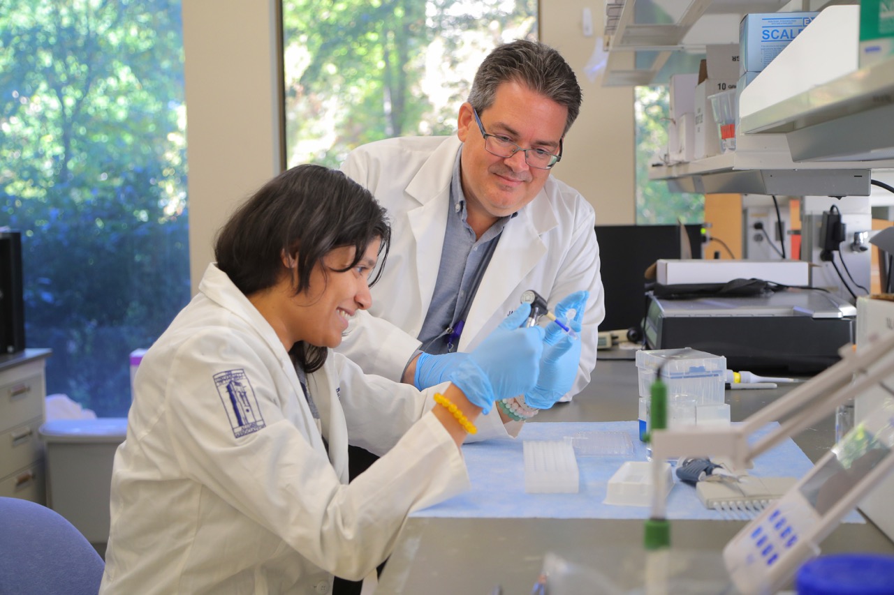 A lab student working in the lab with  Dr. James Burkett, an assistant professor of neuroscience, instructing the student.
