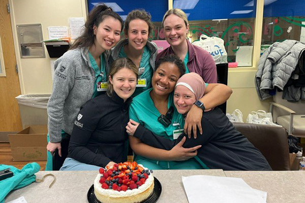 Jessica, Hailey, Haley G, Elle, Tannice, and Yasmin with cake in a clinical setting