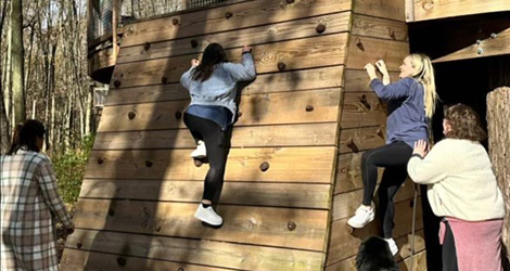 Resident climbing a wooden wall on a playground on retreat