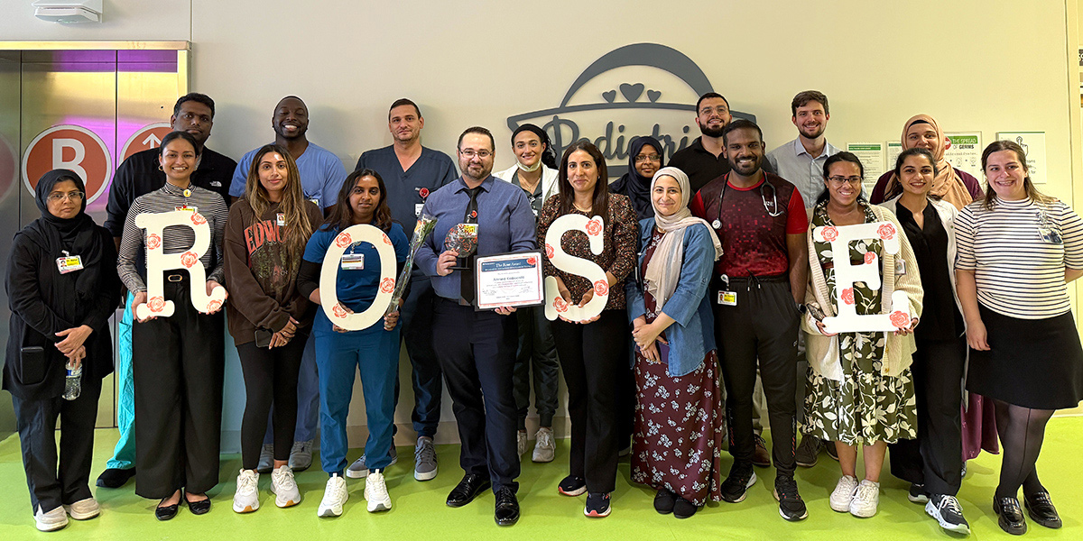 Group of pediatric department staff gathered for the ROSE Awards, standing together and smiling while holding large decorative letters spelling “ROSE,” with one team member holding an award certificate at center.