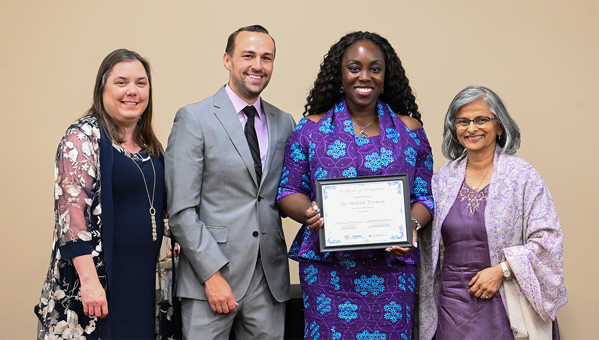 Drs. Bevington, Alecusan and Thomas stand with Department Chair Dr. Deepa Mukundan, with Dr. Thomas holding an award certificate during a recognition event.