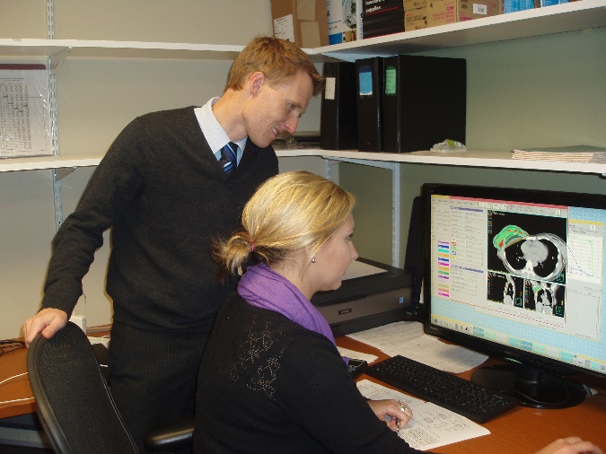 A faculty member is looking on with a student on a computer.