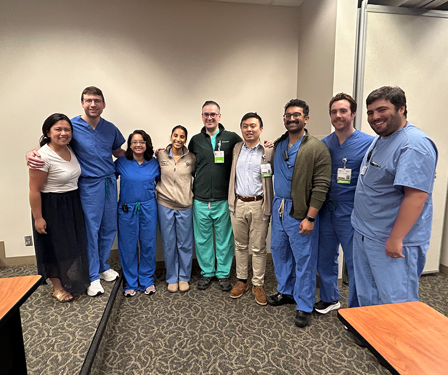 Residents take a group photo following grand rounds in a classroom