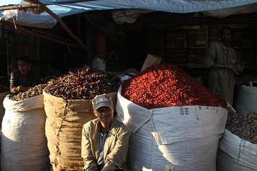 man sits infrom of huge bag of pepper