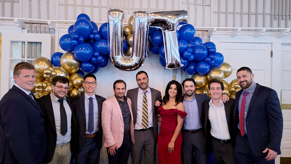 Group photo of graduating residents in front of balloons that spell out UT.