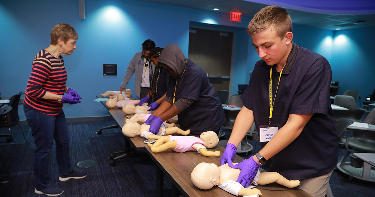 Cuper Kania practices infant CPR during CampMed inside a classroom on campus.