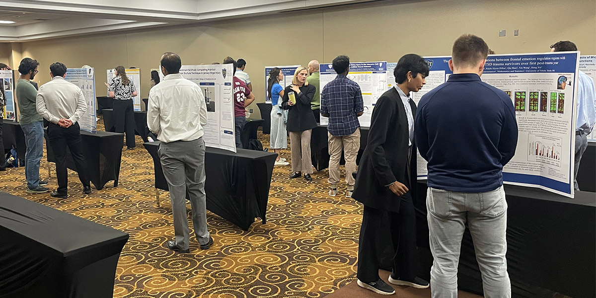 Attendees view and discuss research posters during the Medical Student Research Symposium, which showcased 50 second-year medical students' summer research projects.