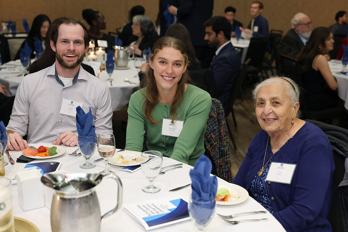 Students Nathan Jones and Samantha Thomas sit at a table with Dr. Amira Gohara at the event. 