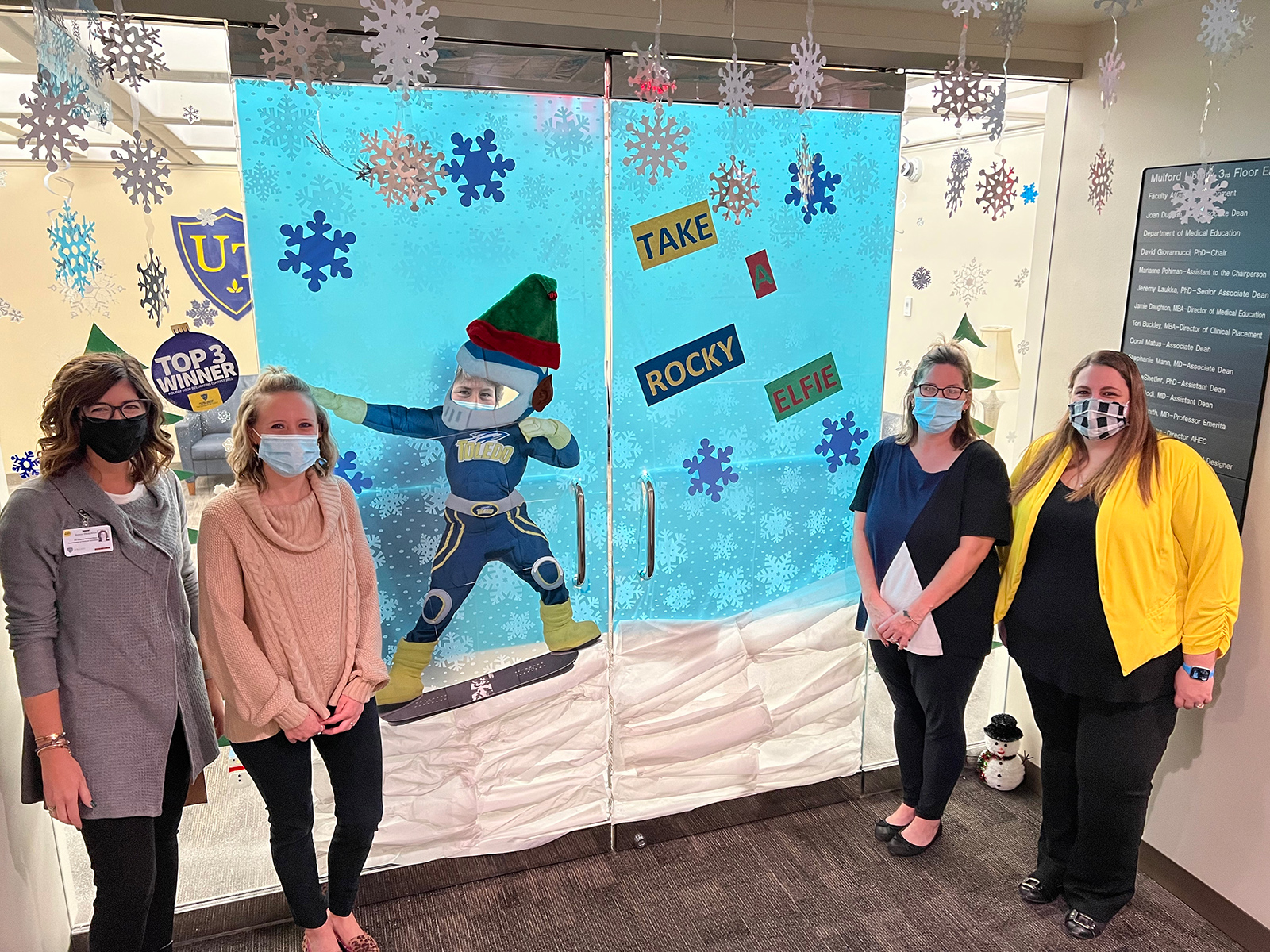 Staff members stand in front of their decorated door